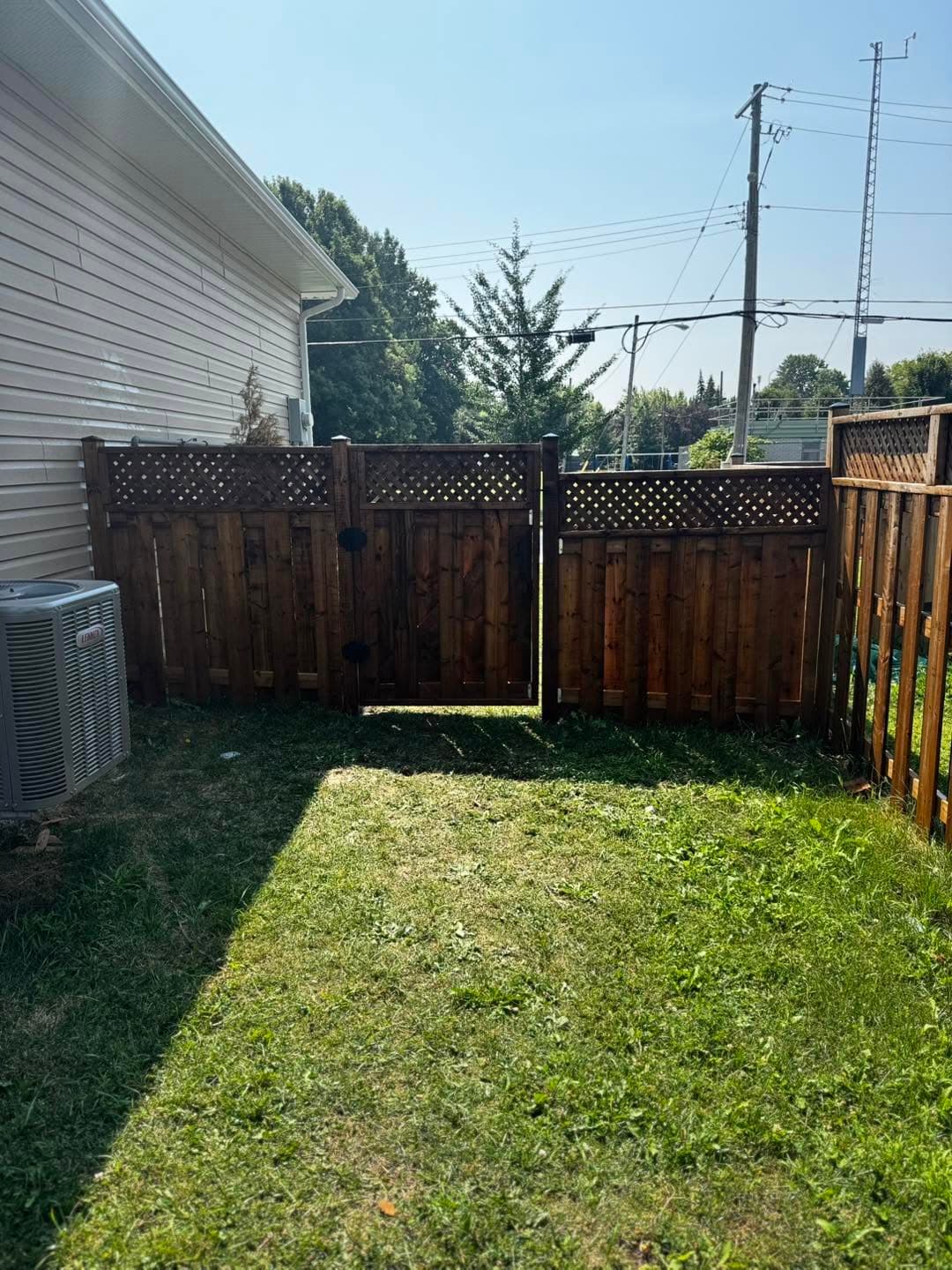 Completed wood fence corner beside a fresh lawn
