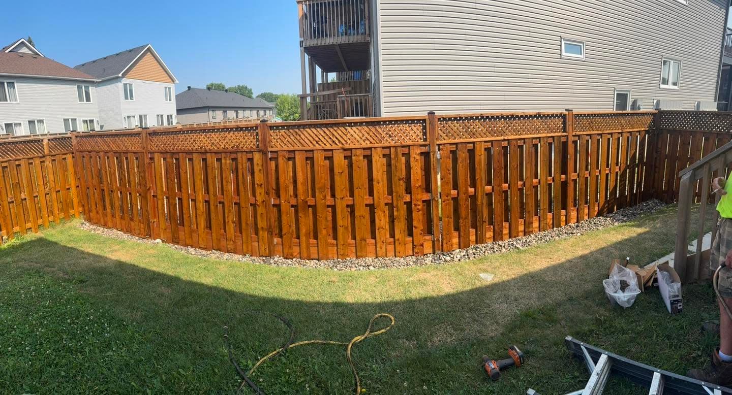 Long stained wood privacy fence with lattice top